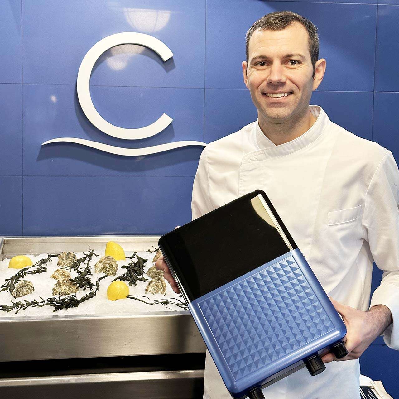 Chef holding an AVATAR ozonated water system beside oysters on ice